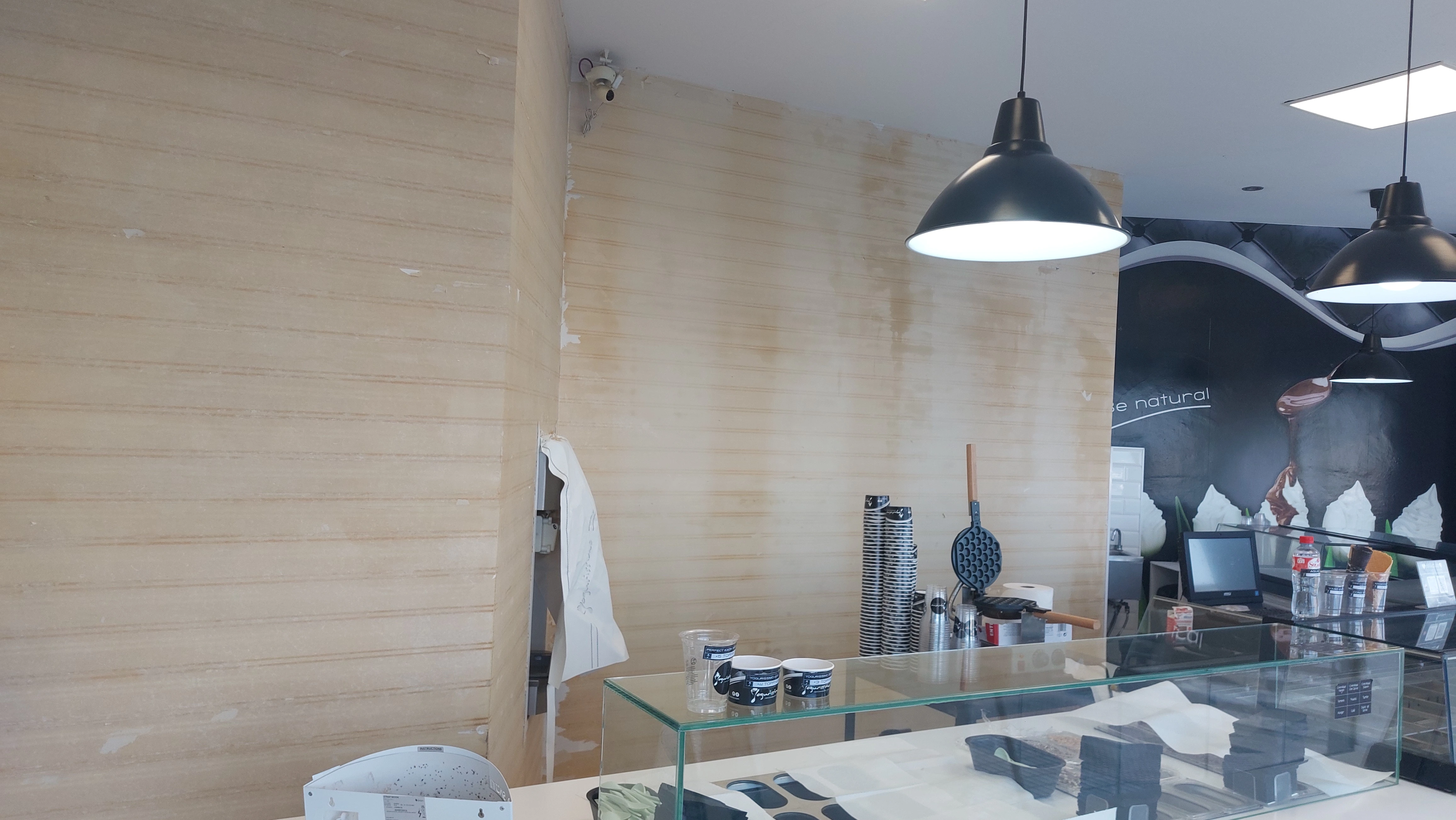 Pared de heladería con restos de cola tras arrancar el papel pintado viejo