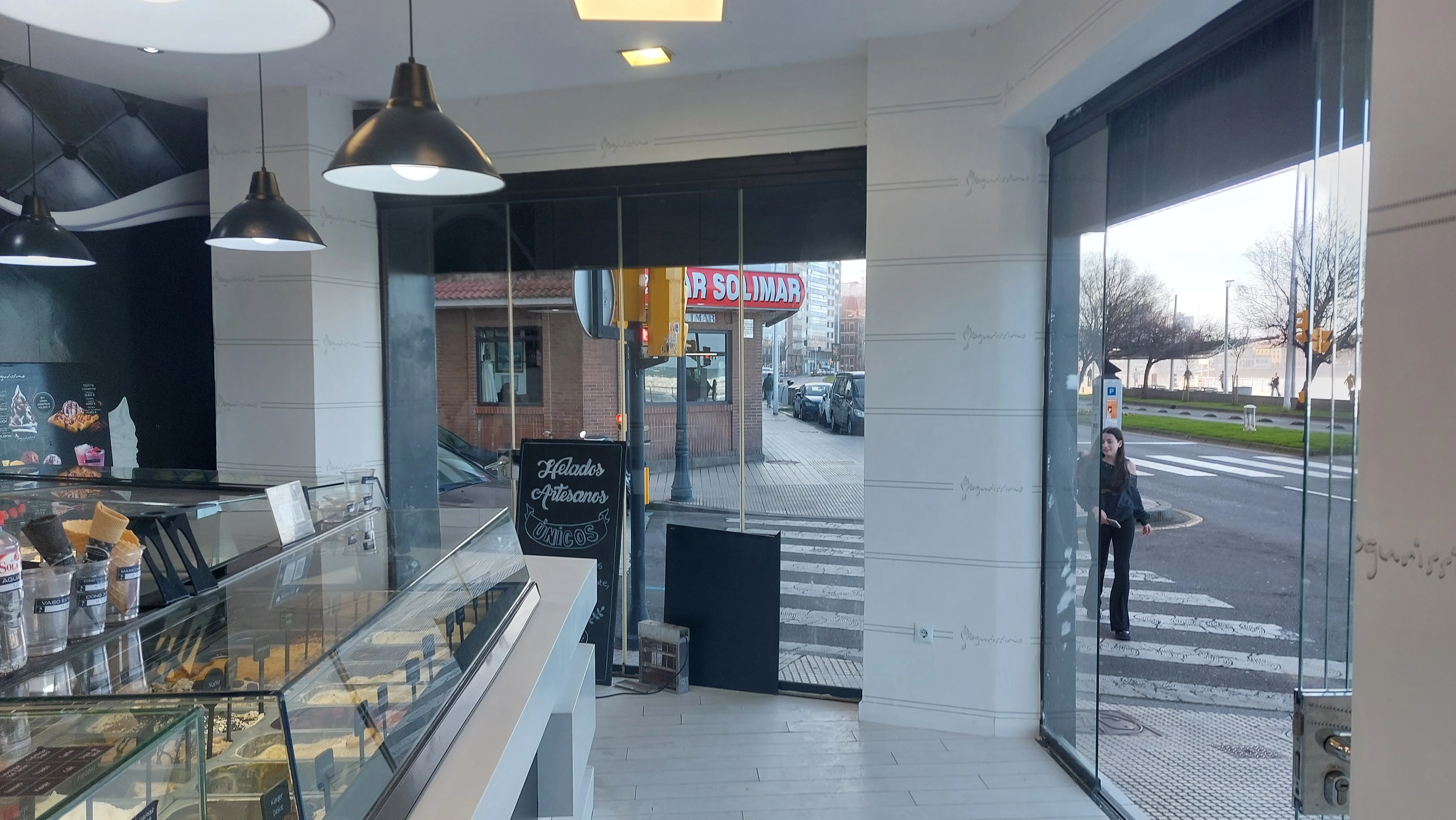Interior de heladería Yogurissimo empapelada, con papel de marca y cuadros decorativos en Gijón